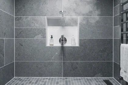 Mitigeur douche en niche avec robinet chromé monté à mi-hauteur sur carrelage grand format gris dans une salle de bain moderne