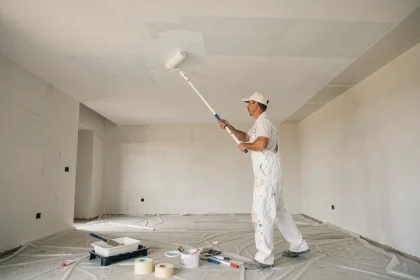 Peintre professionnel appliquant de la peinture blanche au rouleau sur un plafond de maison neuve de 50m2